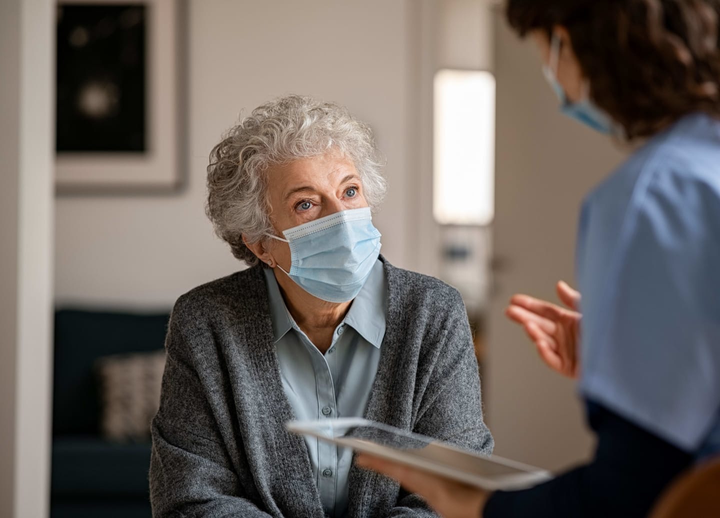A person in a mask talking to a health care provider