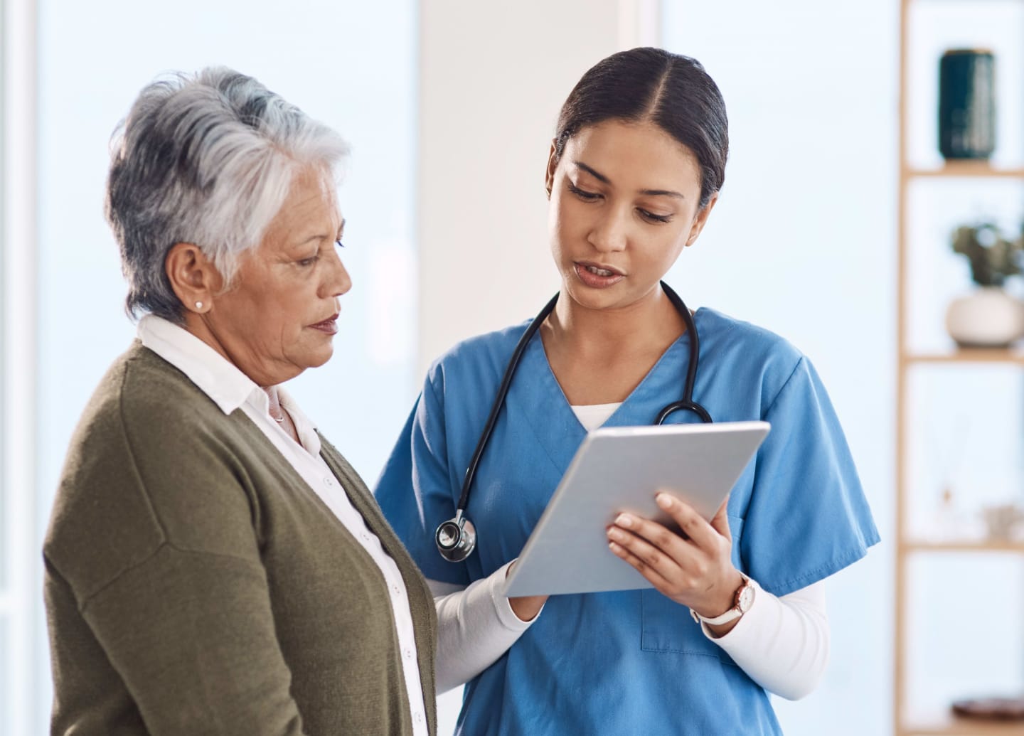 Medical assistant with patient reviewing information on a tablet
