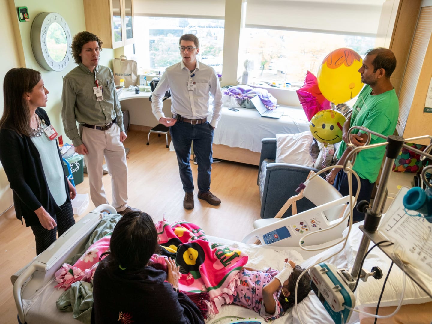 A family gathered around a child in a hospital bed