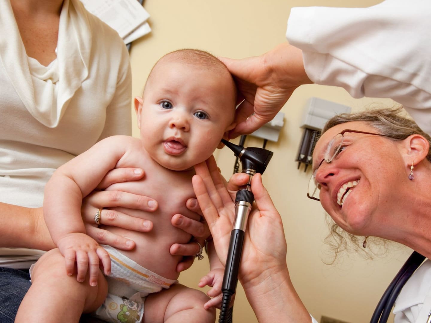 A baby having its ears checked by a physician