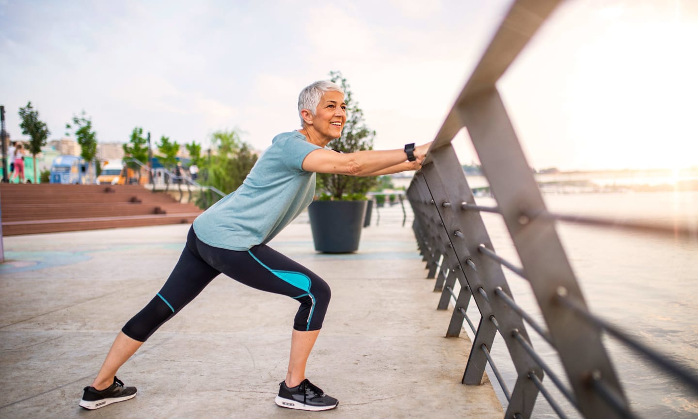 A person stretching against a railing