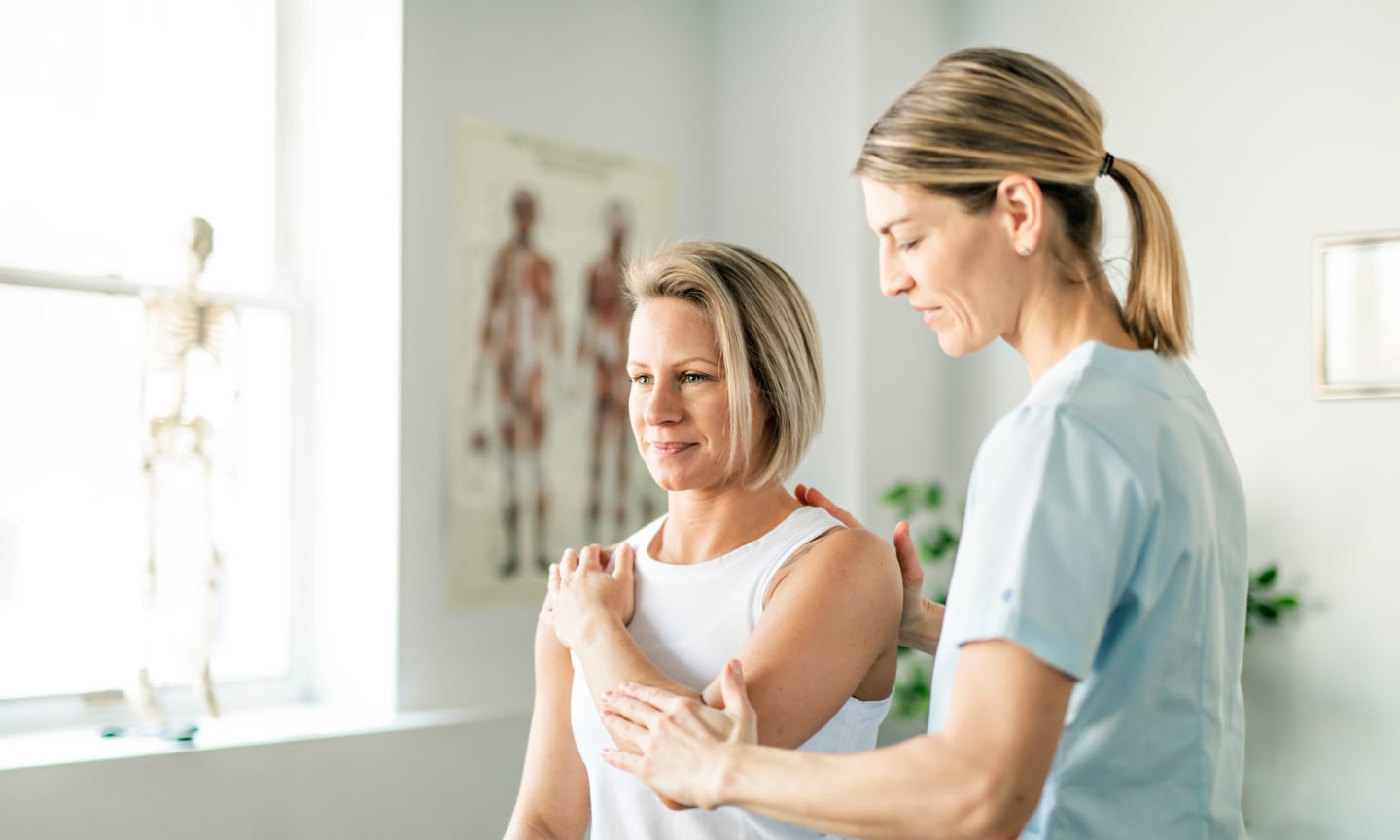 A patient holding their shoulder while working with a physical therapist