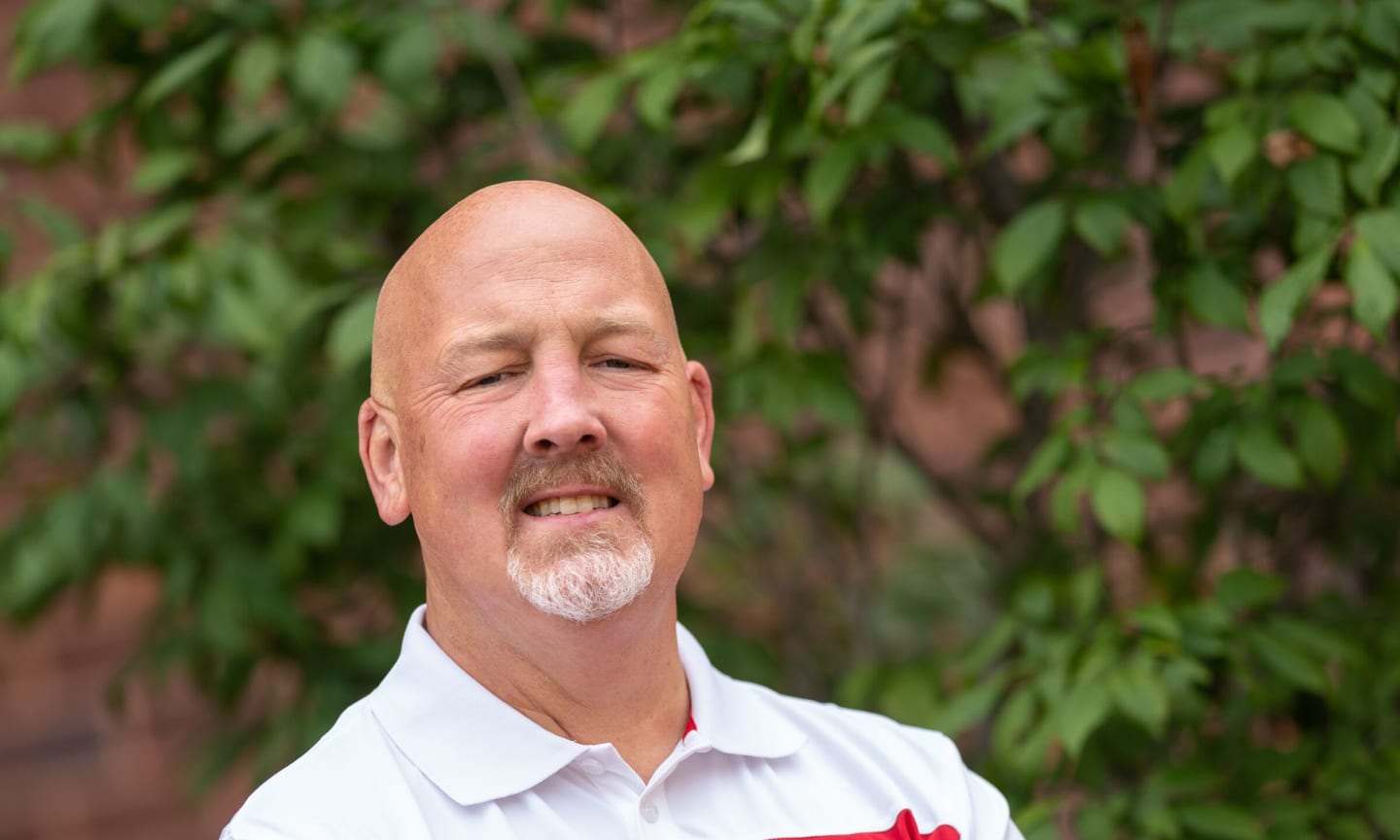 David Peterson standing with his arms crossed in a white Wisconsin Badgers polo