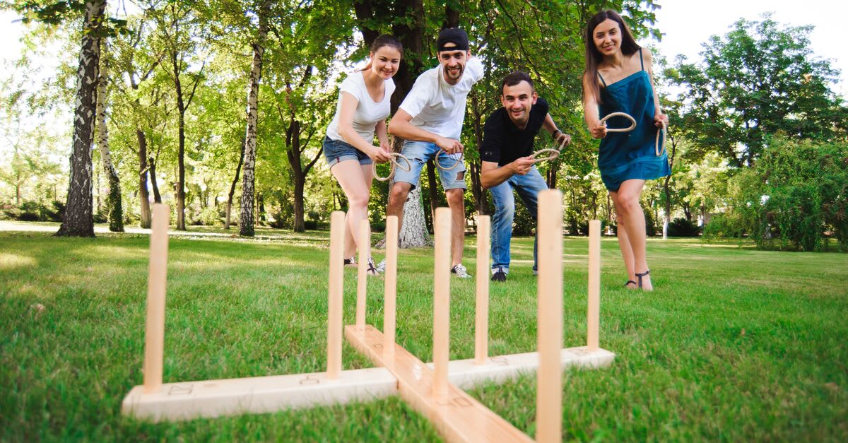 Four people playing a ring toss game in a yard
