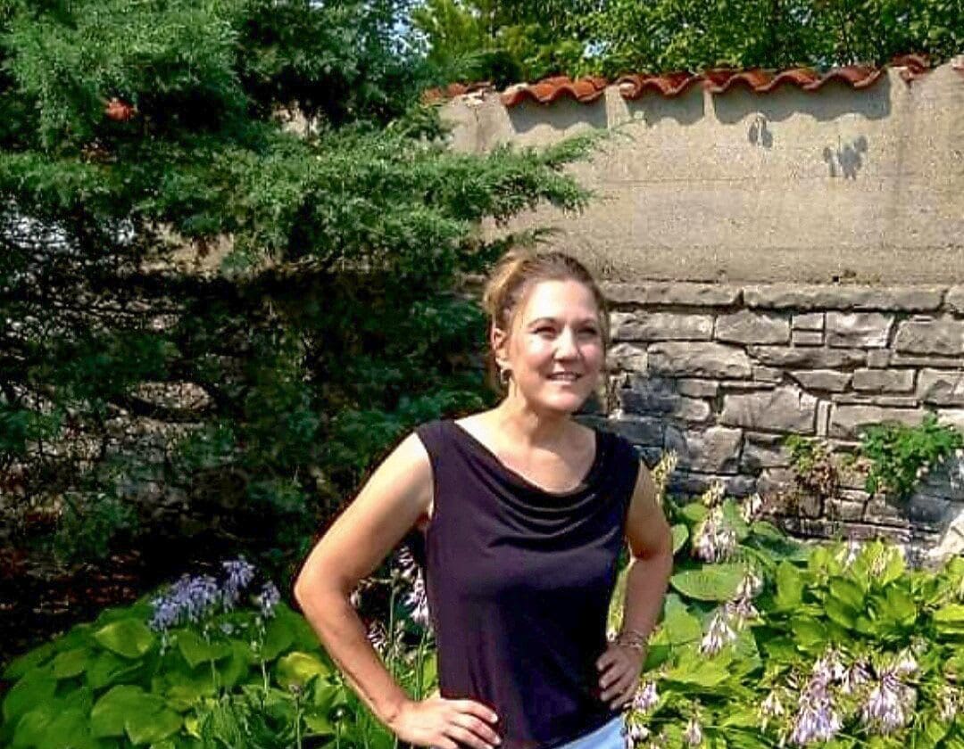 Jennifer Johnson standing in front of a flower garden