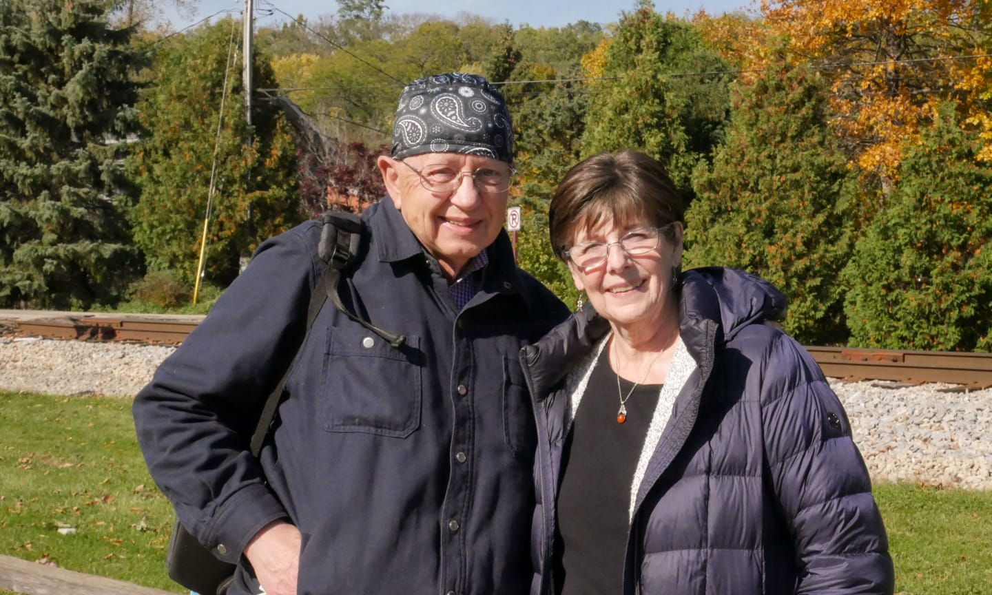 Daniel Ferguson and his wife Rene standing in front of railroad tracks on a fall day