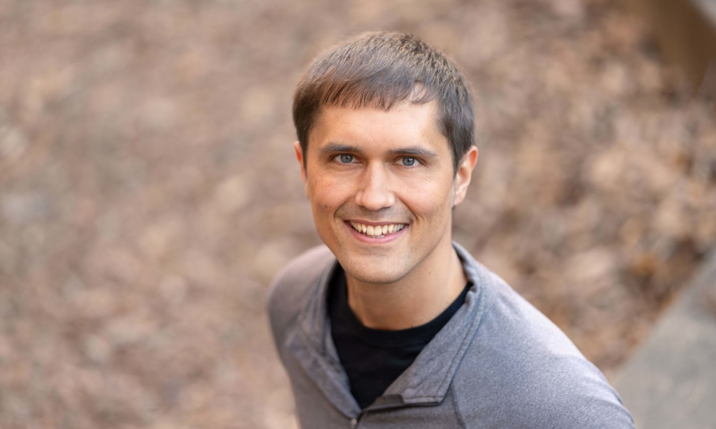 Man, wearing grey shirt and smiling.