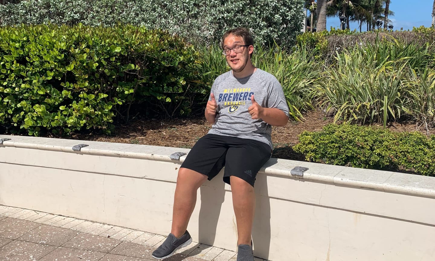 Colton Maron sitting on a wall, giving two thumbs up