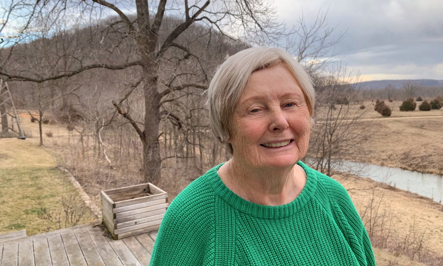 Woman, outside, smiling and wearing a green sweater.