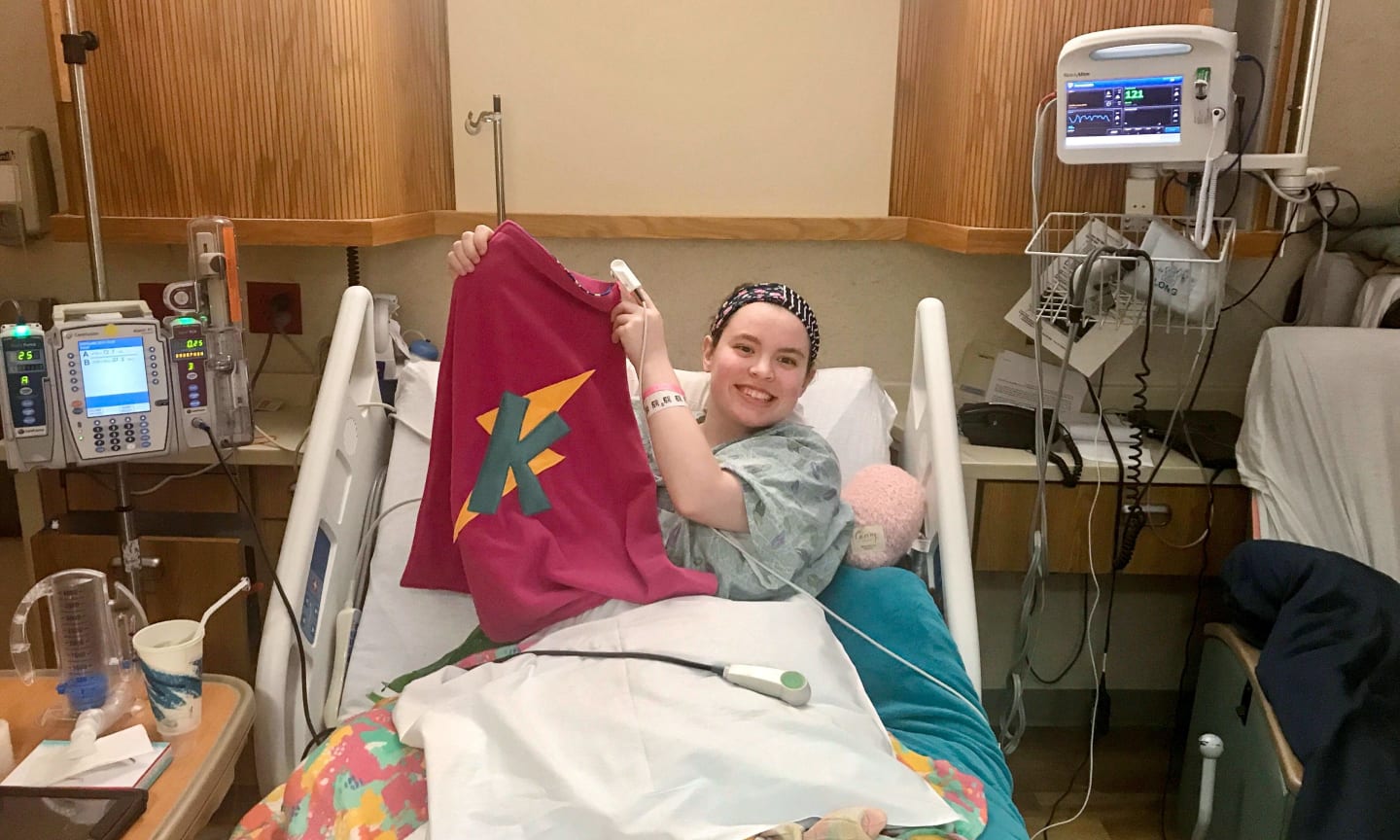 Kristen, smiling in her hospital bed after her renal autotransplant surgery.