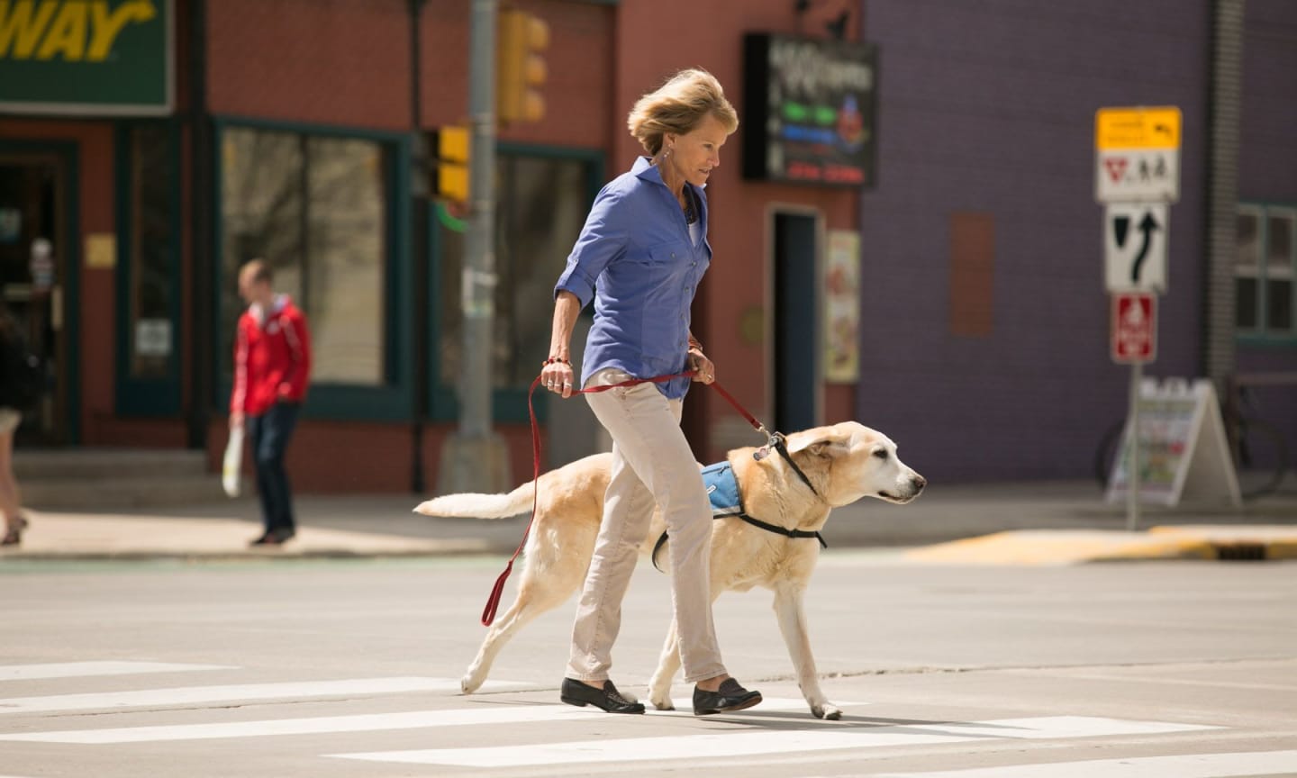 Lisa Steinkamp walking her dog across a crosswalk
