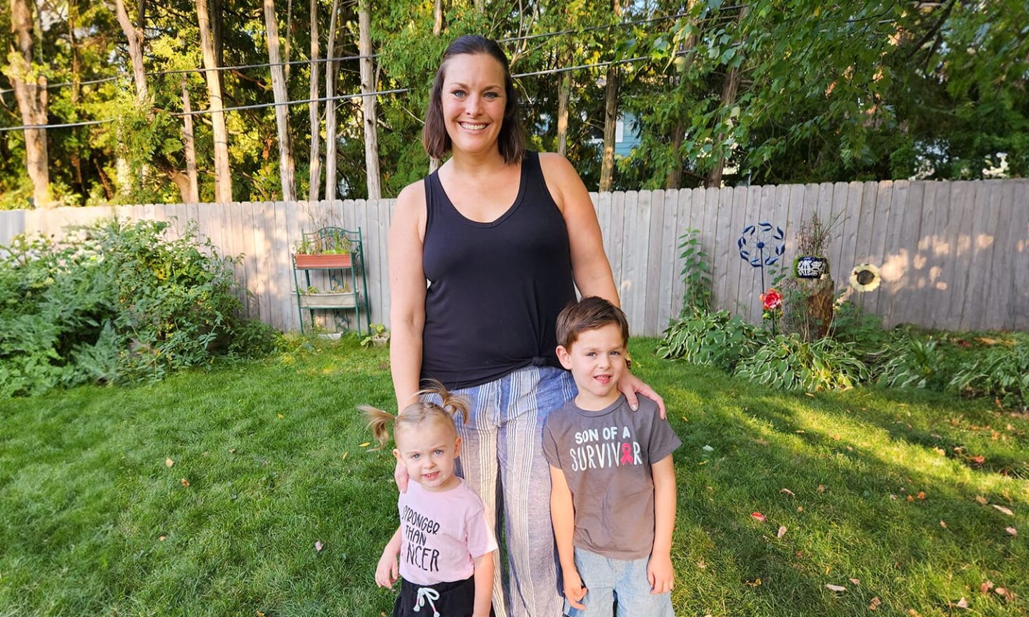 Andrea Moskol standing in a yard with her two children