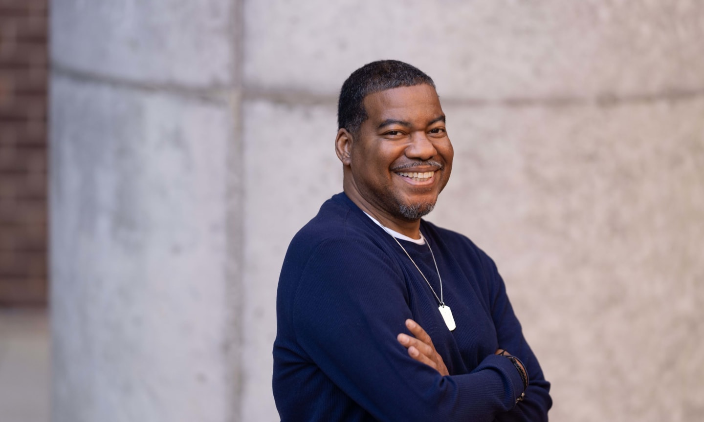 Man wearing sweater standing outside and smiling. 