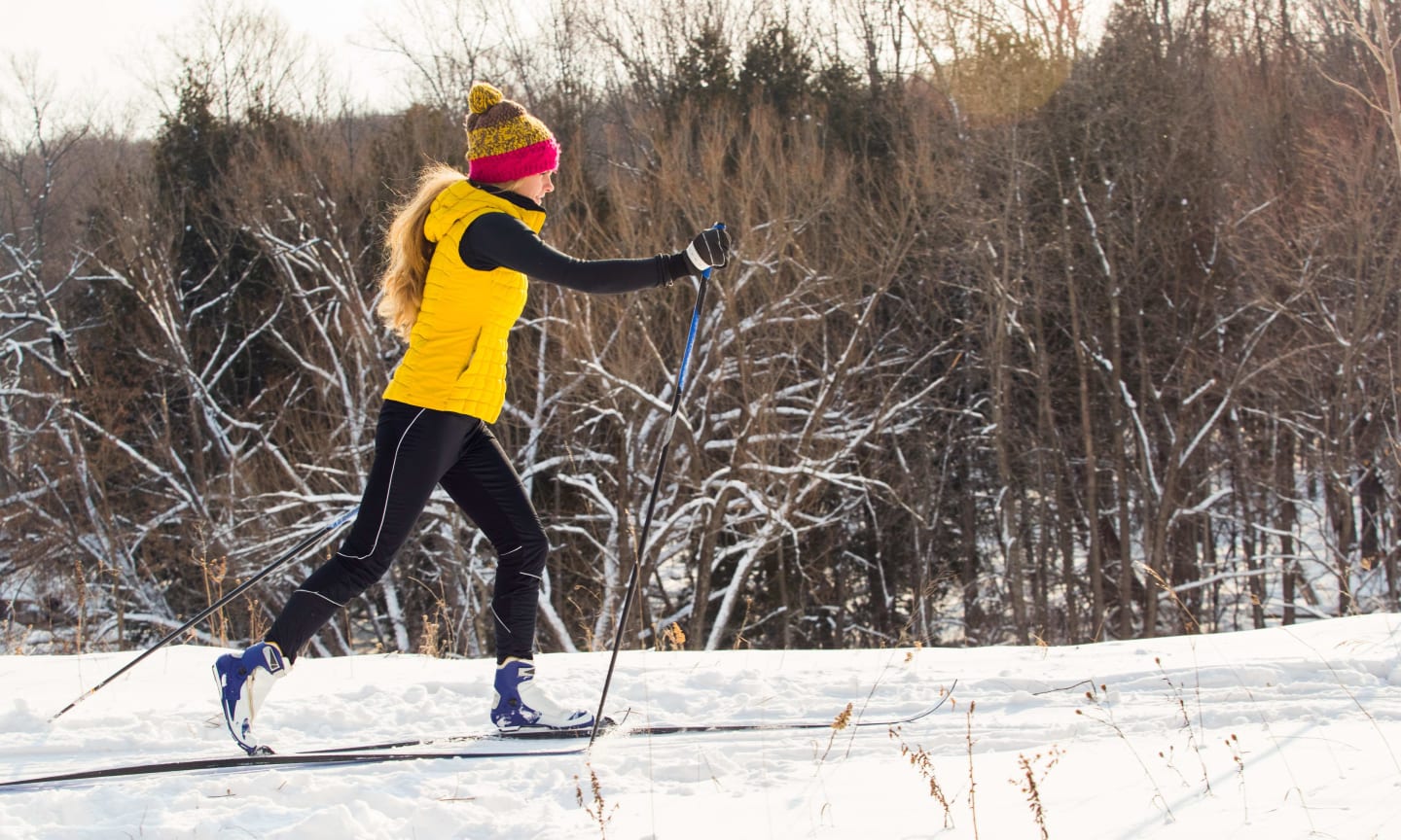 A person cross country skiing in the classic technique along a tree-lined trail