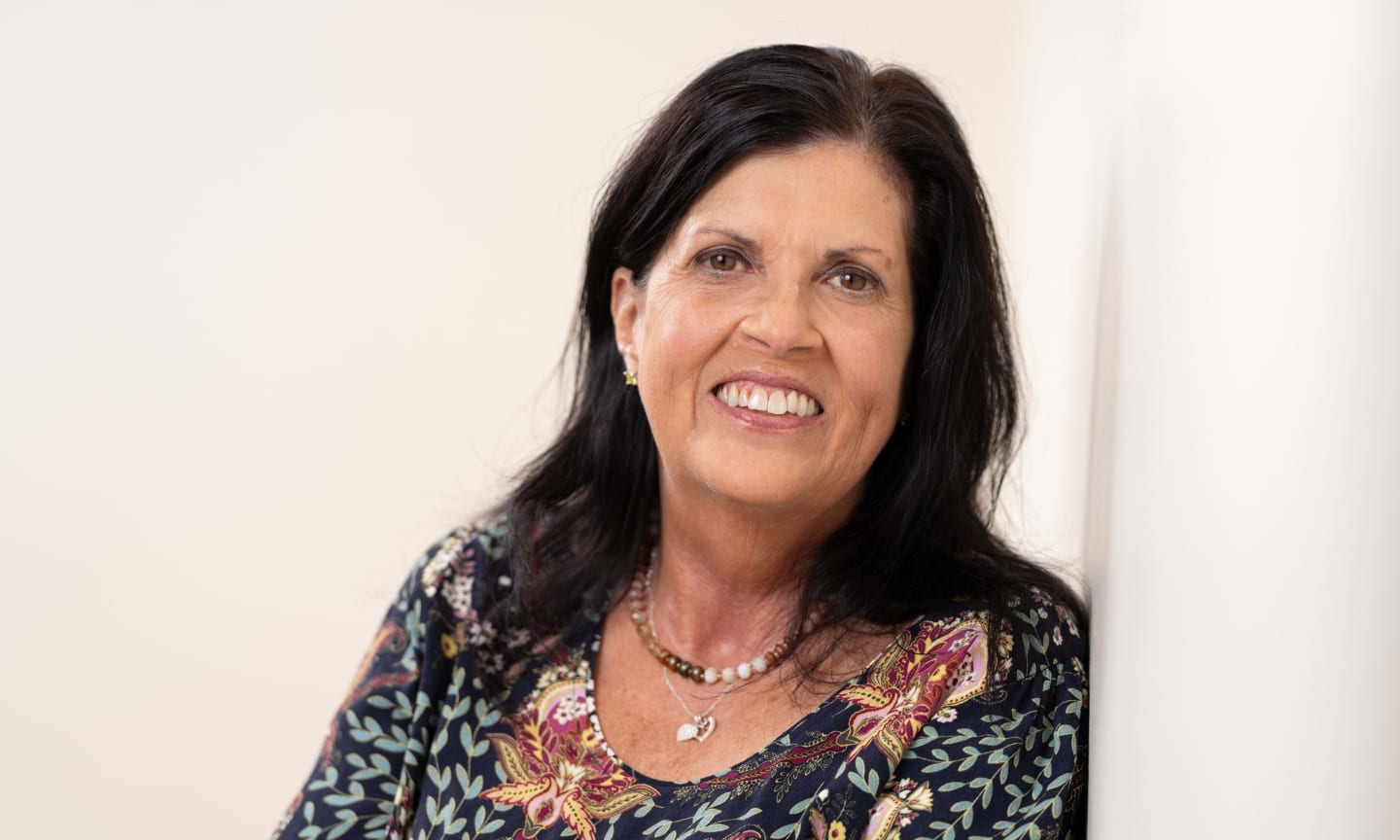 Woman leaning against wall and smiling.