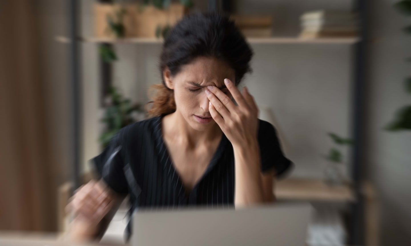 Close up blurred of sick unhealthy Latino woman suffer from dizziness work on laptop at home office. Ill unwell tired Hispanic female struggle with migraine or headache, overwhelmed with screen job.