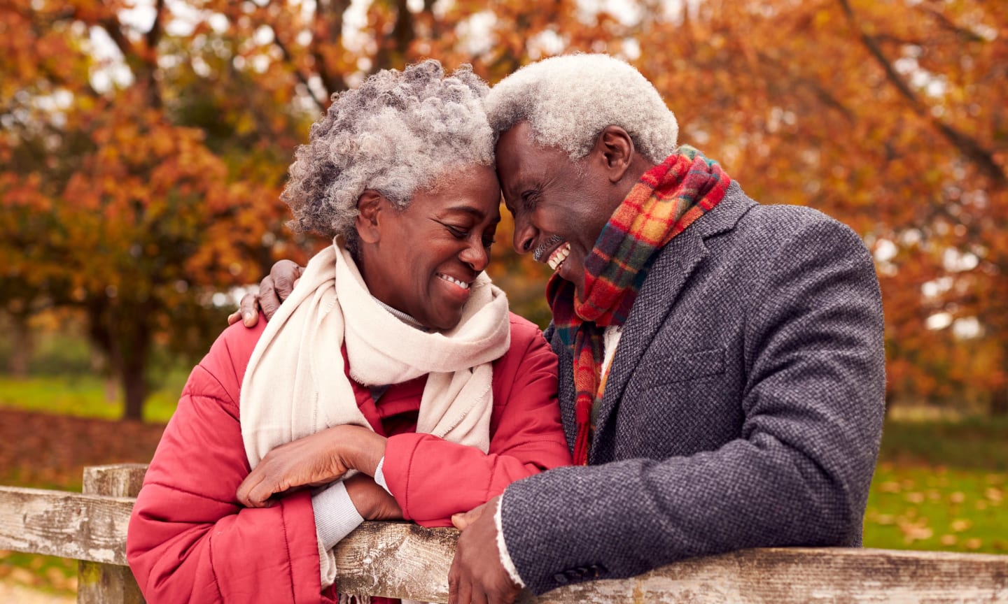 Loving Senior Couple On Walk Through Autumn Countryside Resting By Gate