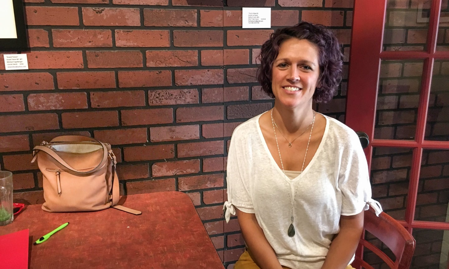 A person sitting at a table in front of a brick wall