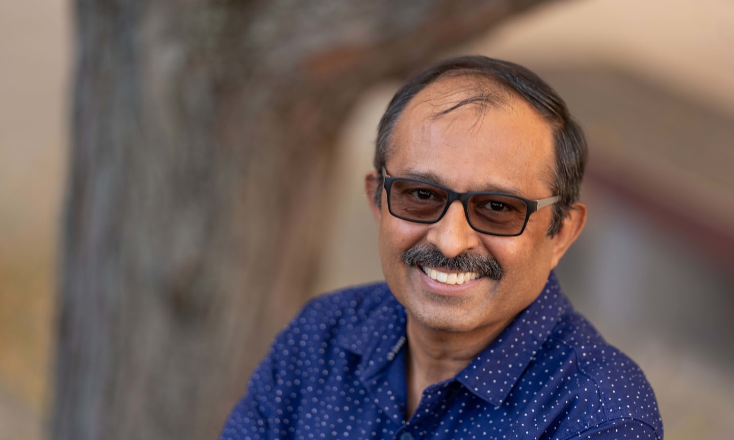 Ram Venkatash Rengasamy portrait, smiling outdoors wearing a button down shirt.