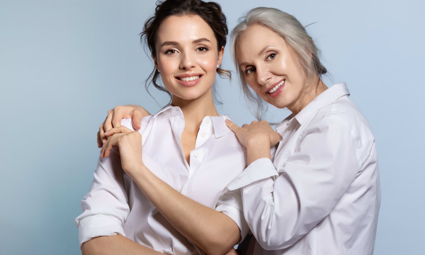 A mother and adult daughter smiling, leaning on each other