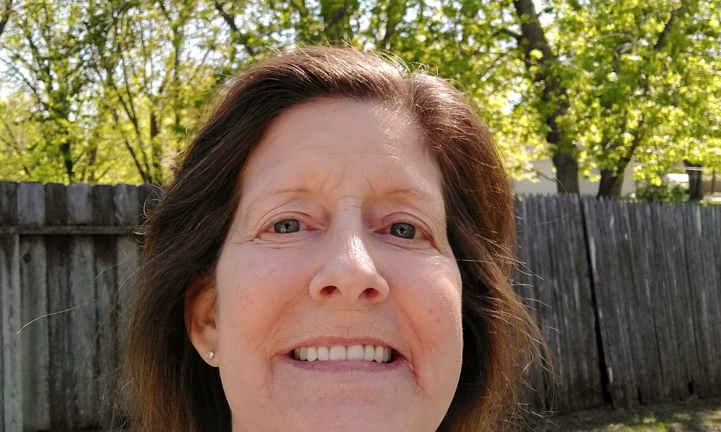 Ann Smitherman, smiling in a fenced yard