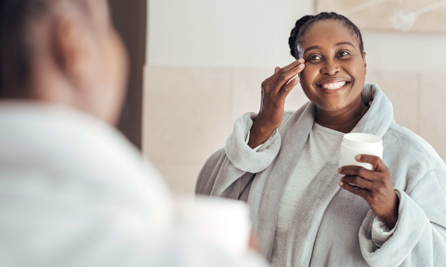Woman applying face cream in mirror