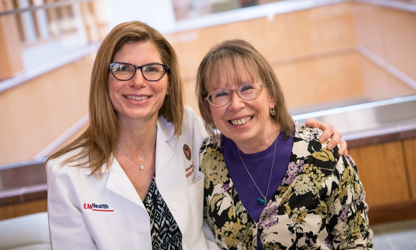 Doctor Sharon Weber and patient Claudia McCormick smiling with arms over each other's shoulders