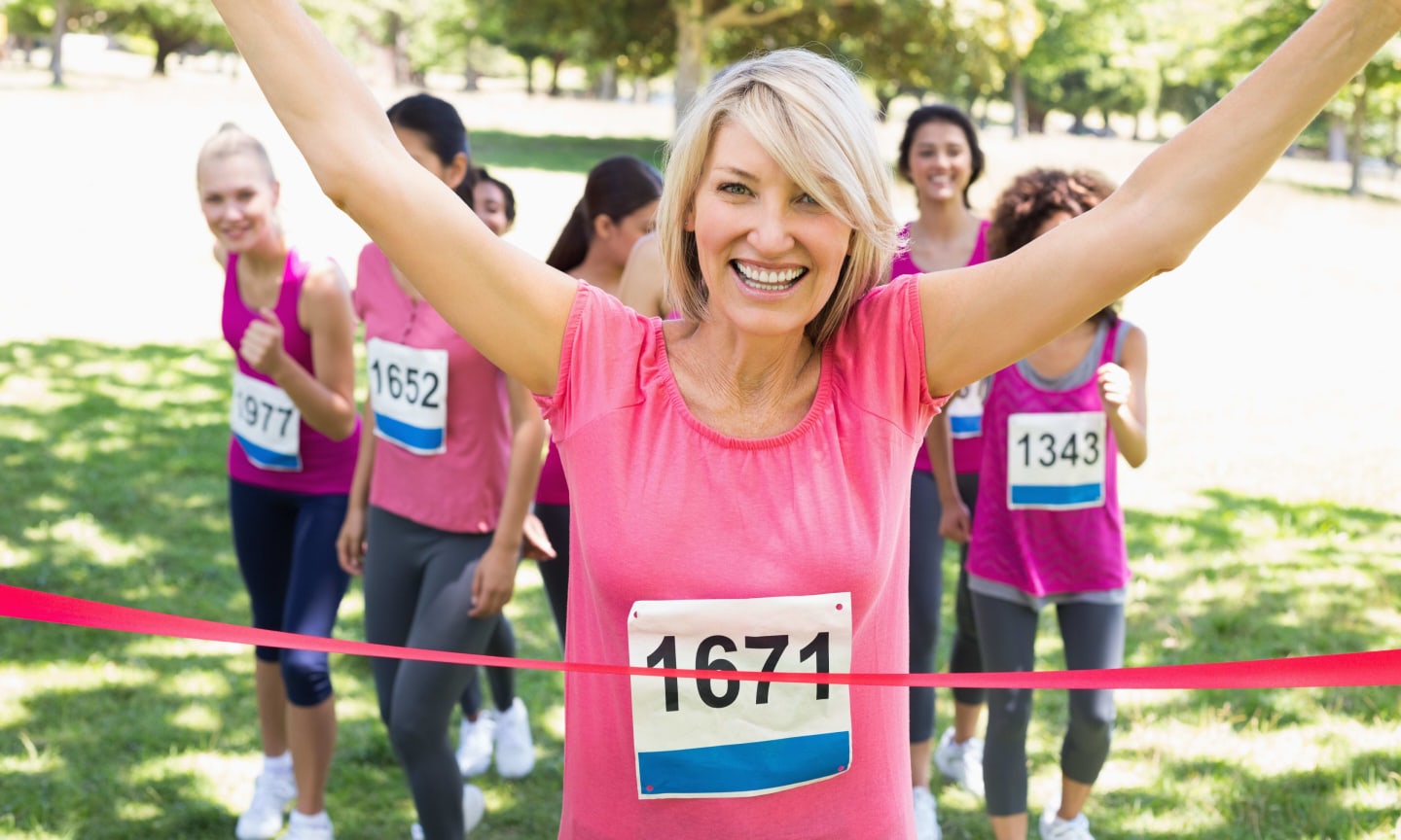 Portrait of happy female winner of breast cancer marathon race at park