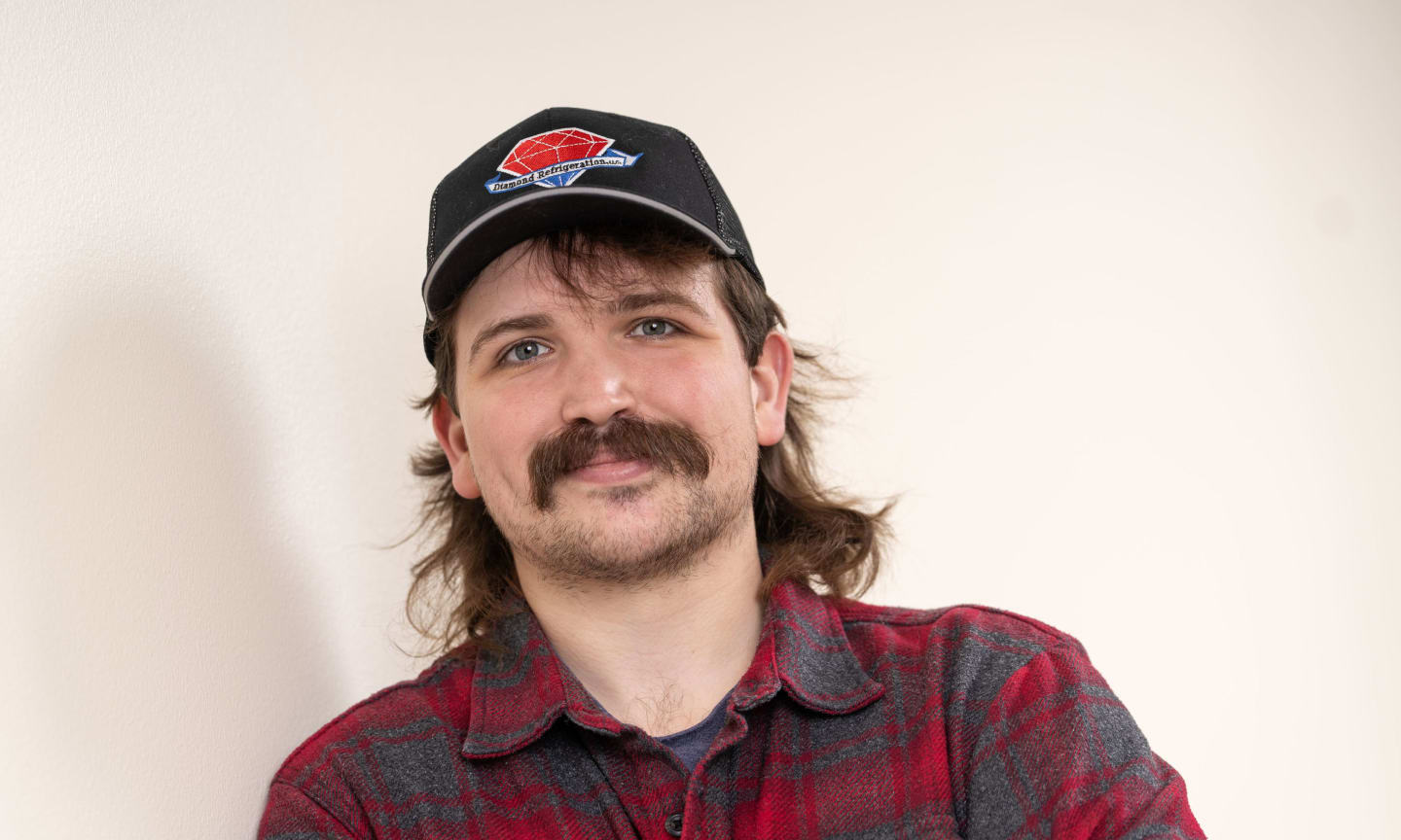 Man with a mustache and a black baseball cap, smiling.