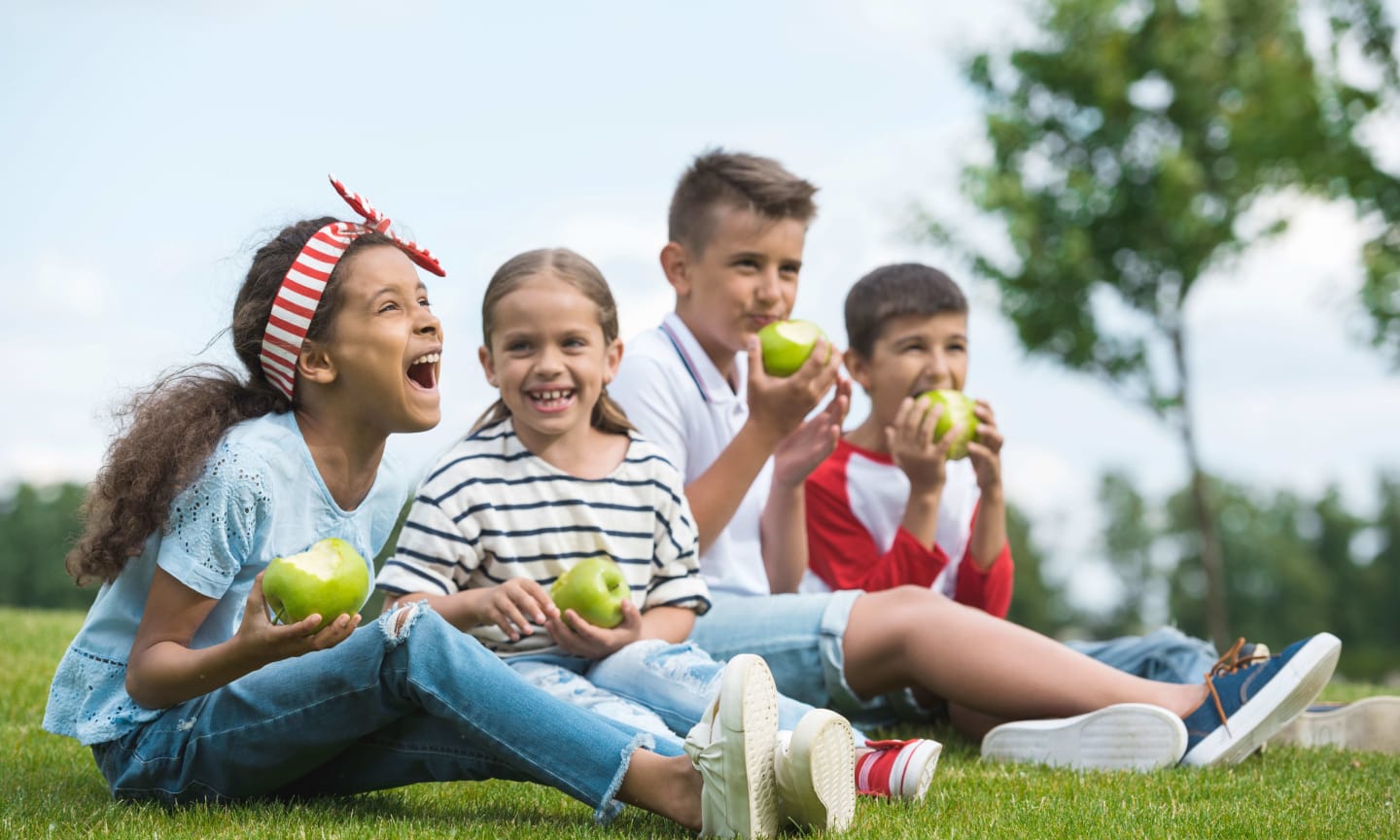 Group of children in a park eating apples