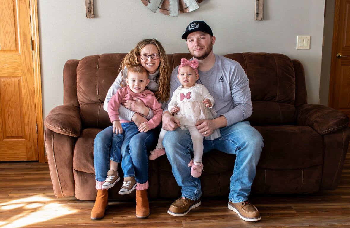 Dani Hansen and her husband and two children sitting on a couch in their house