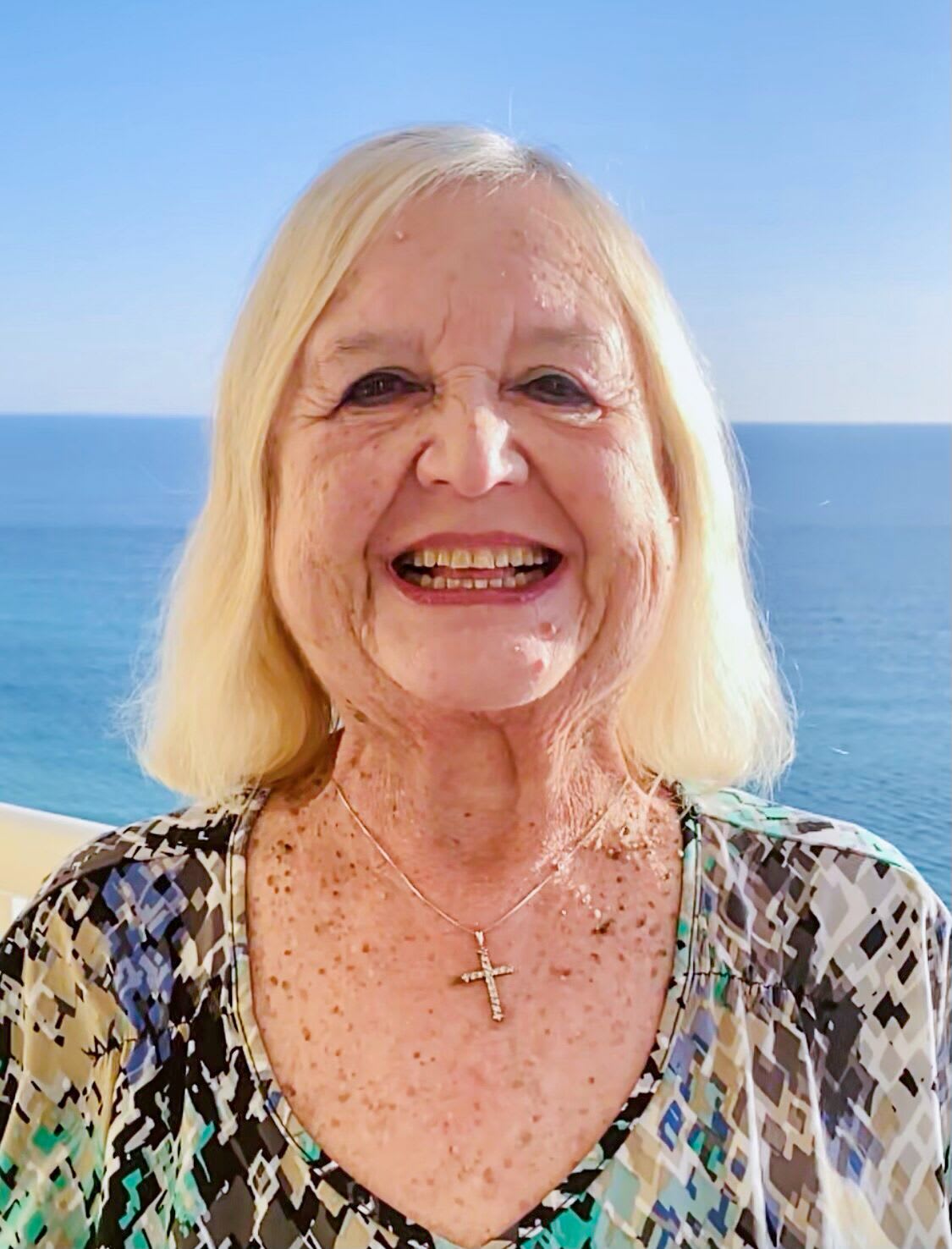 Karen, smiling outside on a beach.