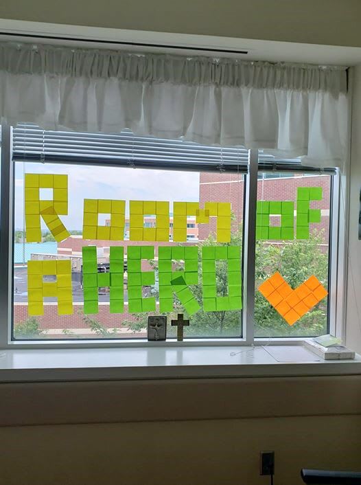 Post-It notes on a window spelling out "room of a hero"