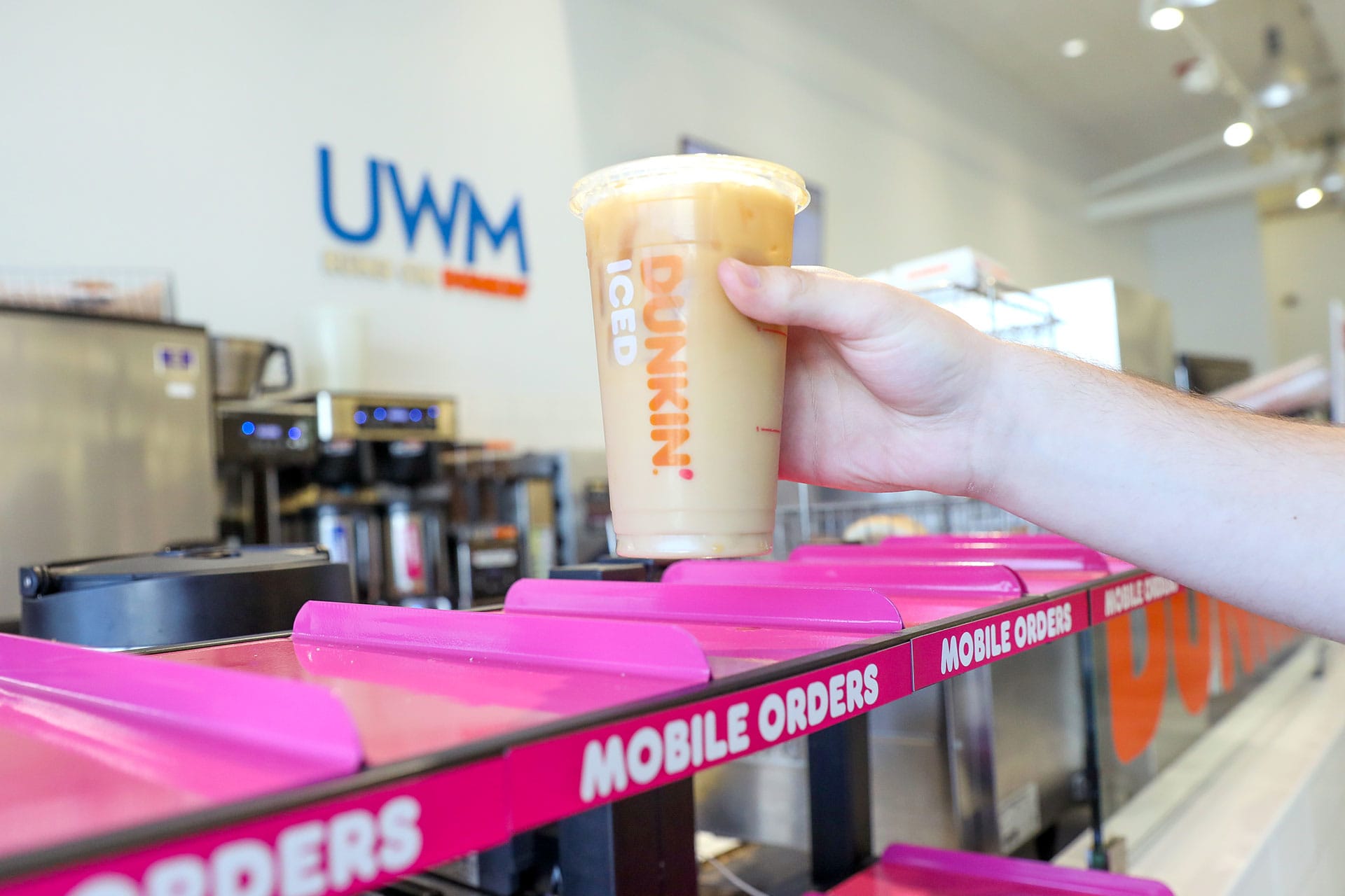 A team member holding a Dunkin coffee cup from the on-site Dunkin