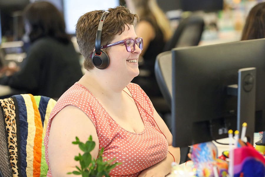 A smiling Client Experience team member at their desk