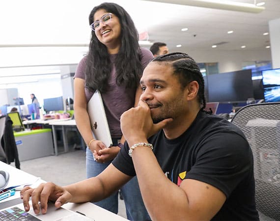 Two Technology team members smiling at a desk