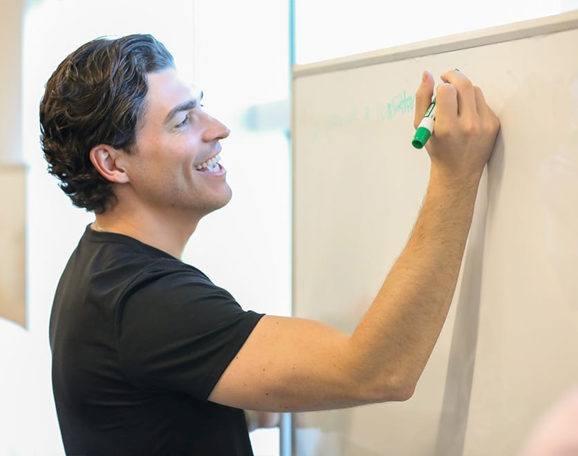A DevOps-X instructor writing on a whiteboard