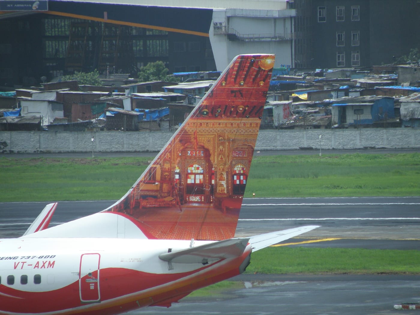 Tail of Air India Express aircraft VT-AXM in front of domestic departure terminal 1C at Chhatrapati Shivaji International Airport