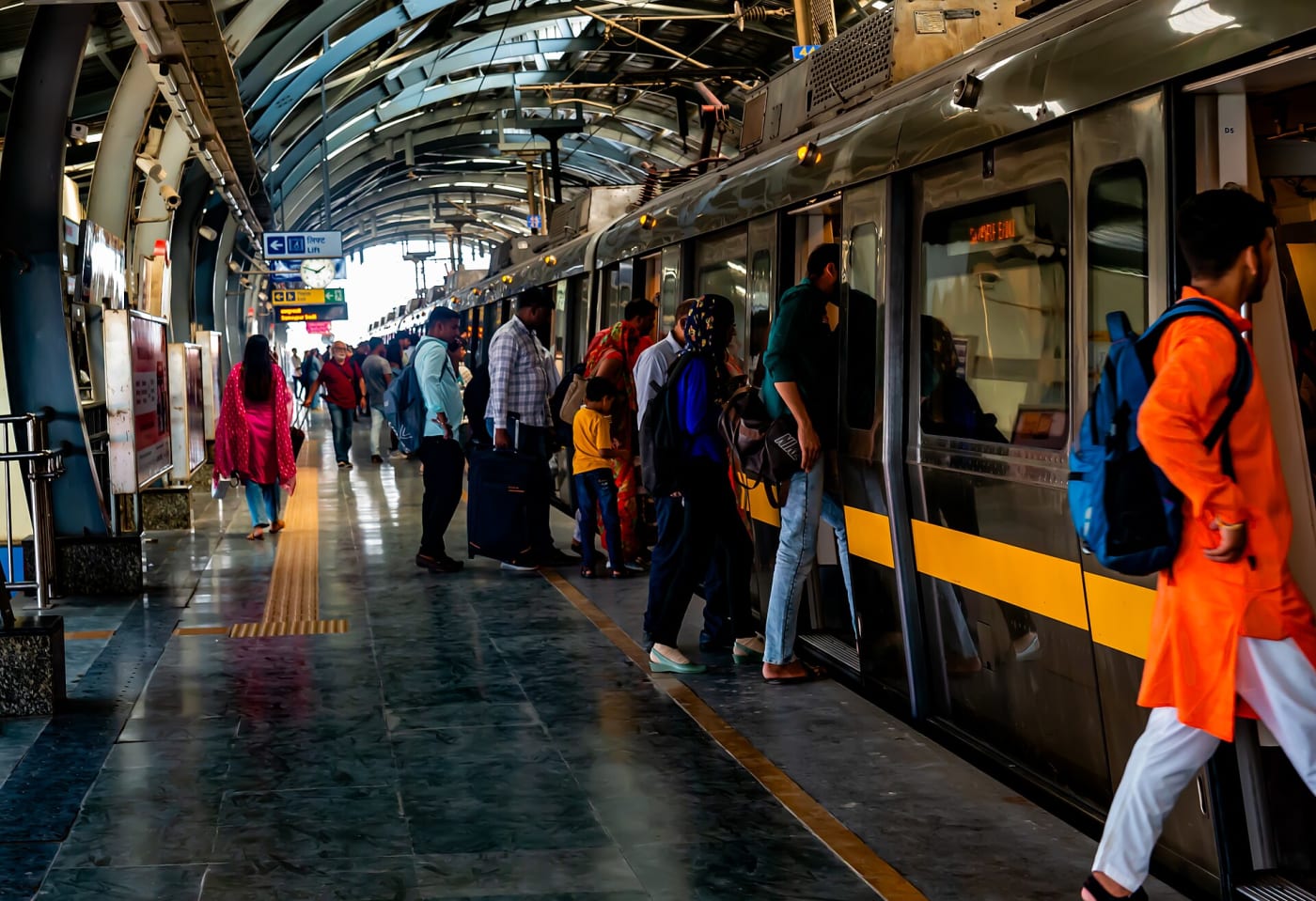 Passengers board a train at Delhi Metro Station. The Delhi Metro is a mass rapid transit (MRT) system serving Delhi and its adjoining satell