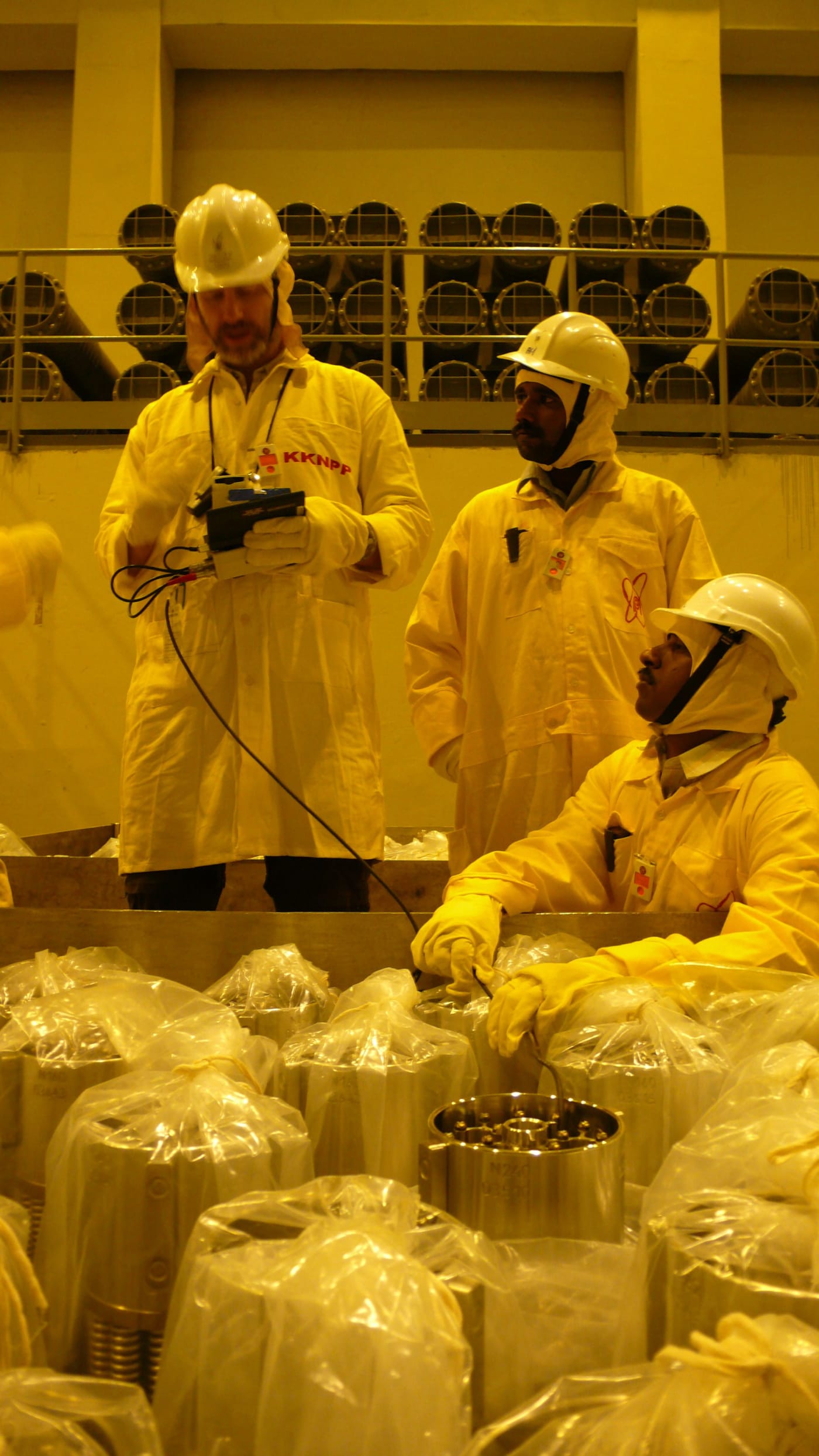 An IAEA inspection team examines nuclear fuel for a new nuclear power plant under construction at Kudankulam, India. Photo Credit: Petr Pavl