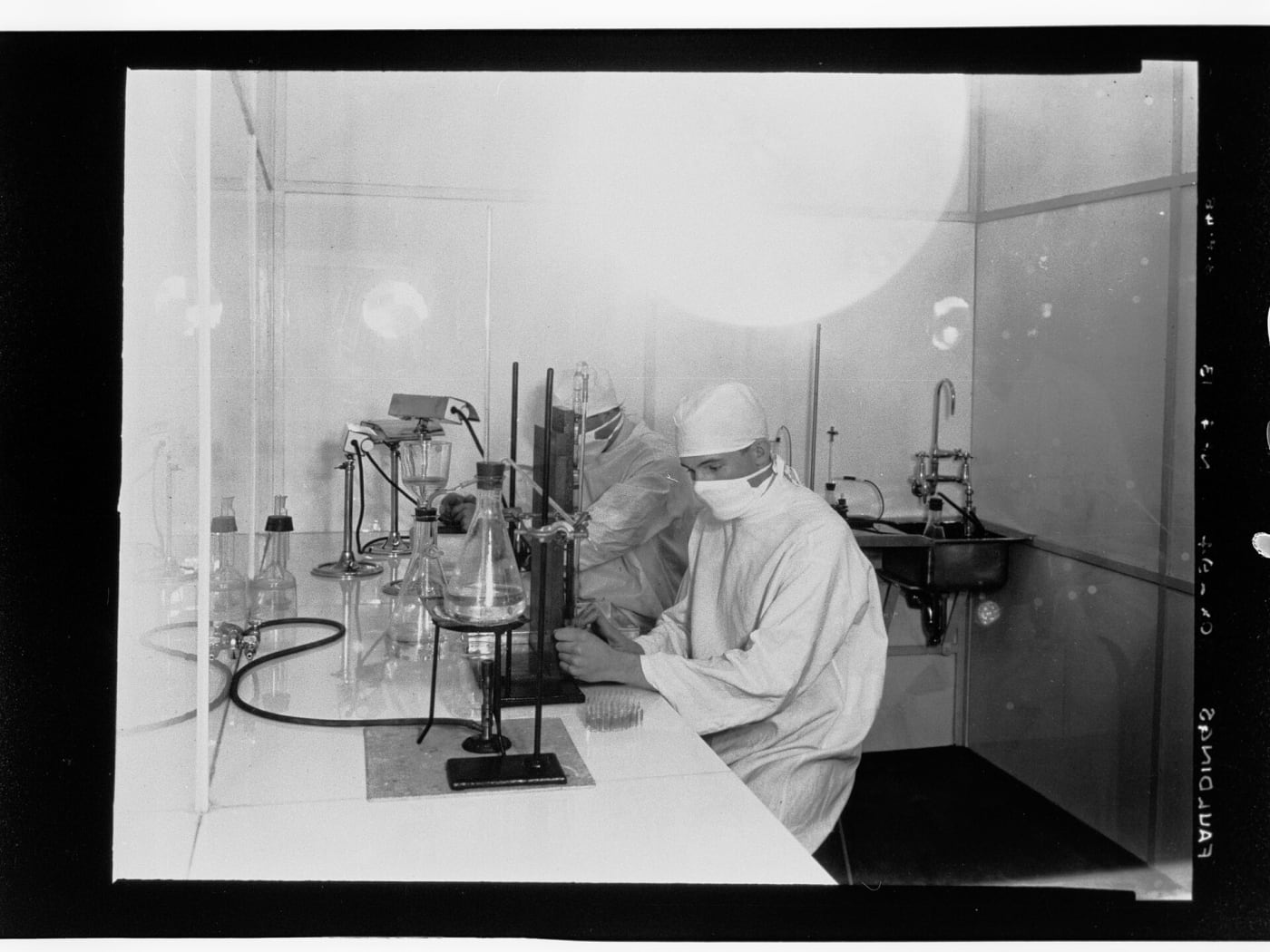 In this photograph two labratory technicians are working possibly on distilling eucalyptus oild. Two of the Faulding company's major innovat