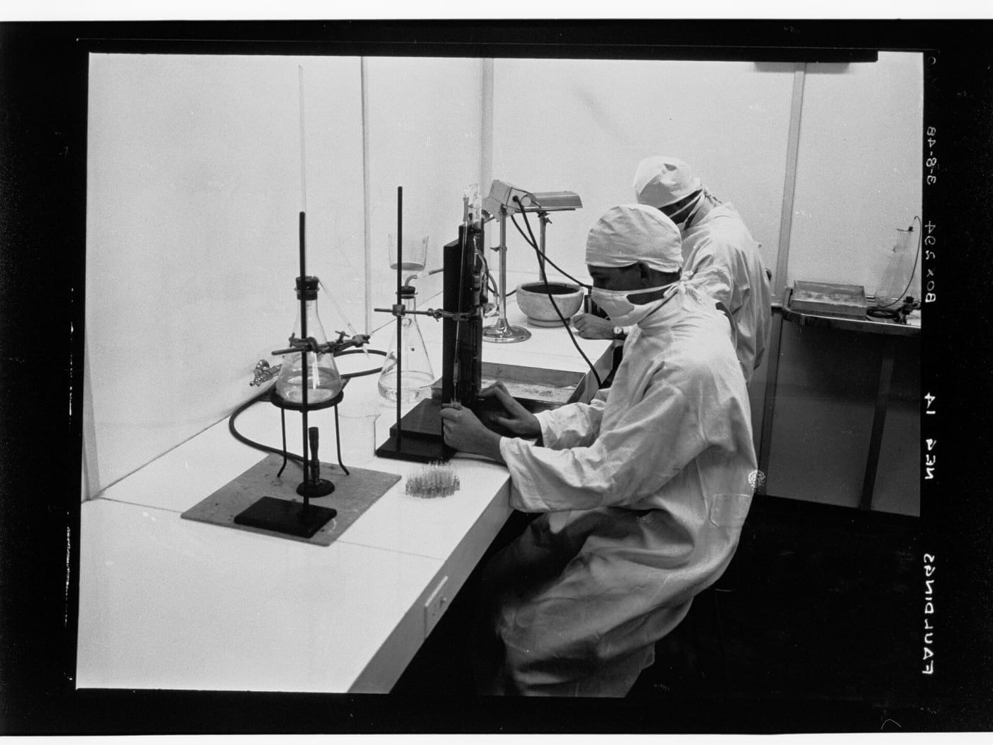 In this photograph two labratory technicians are working possibly on distilling eucalyptus oild. Two of the Faulding company's major innovat