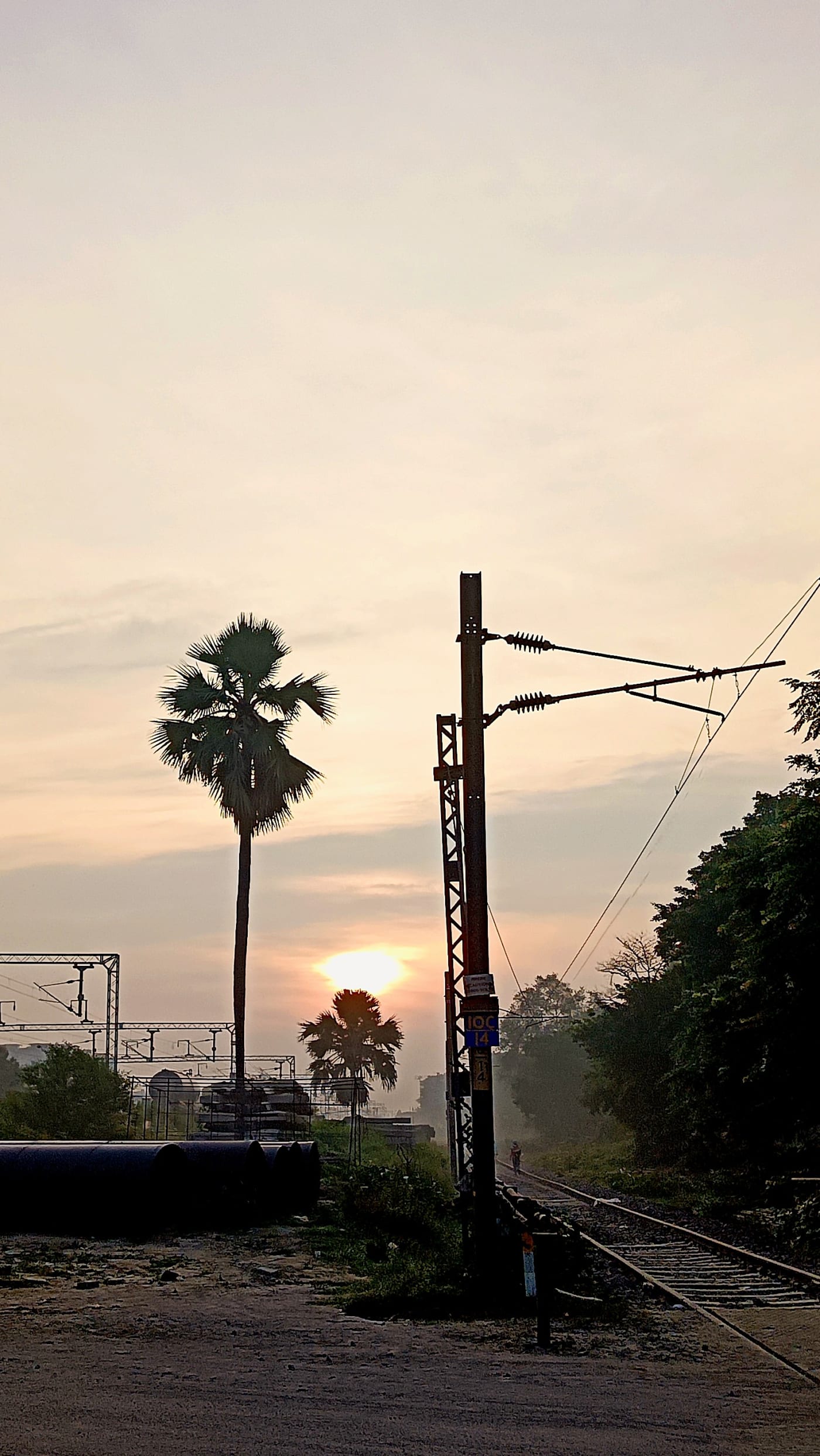 Sunrise near Subedarganj railway station in Prayagraj, Uttar Pradesh, India. The photograph shows electrified railway tracks, overhead elect