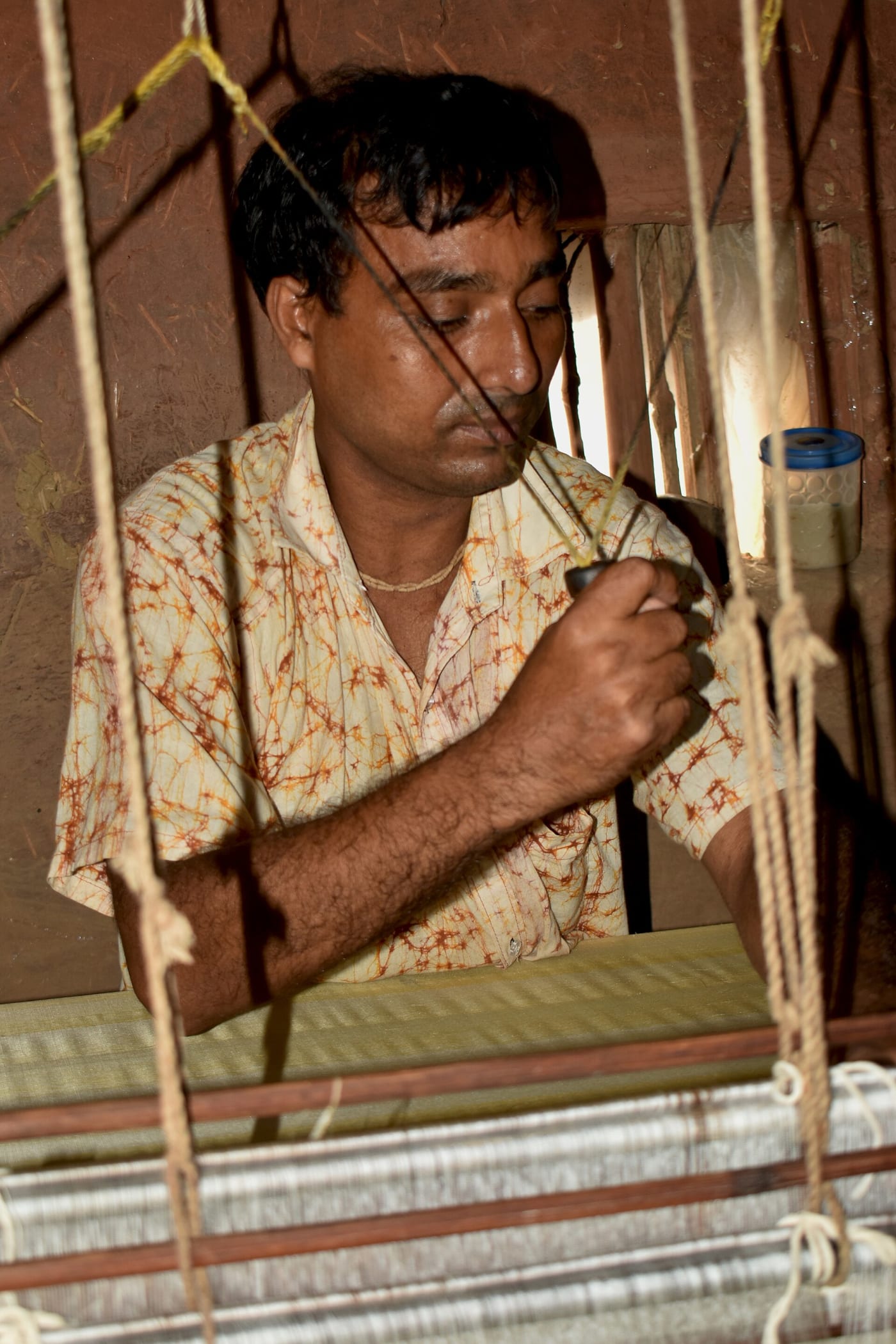 A artisan is weaving Mulberry silk fabric in his handloom, a traditional way of weaving fabric in West bengal.