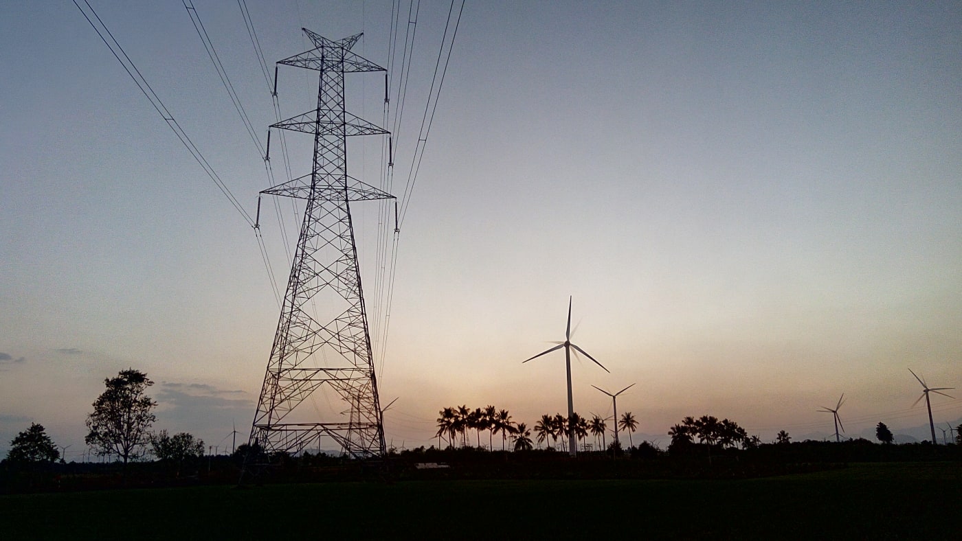 A transmission tower and wind turbines at dusk near Ambasamudram, Theni district, Tamil Nadu.
