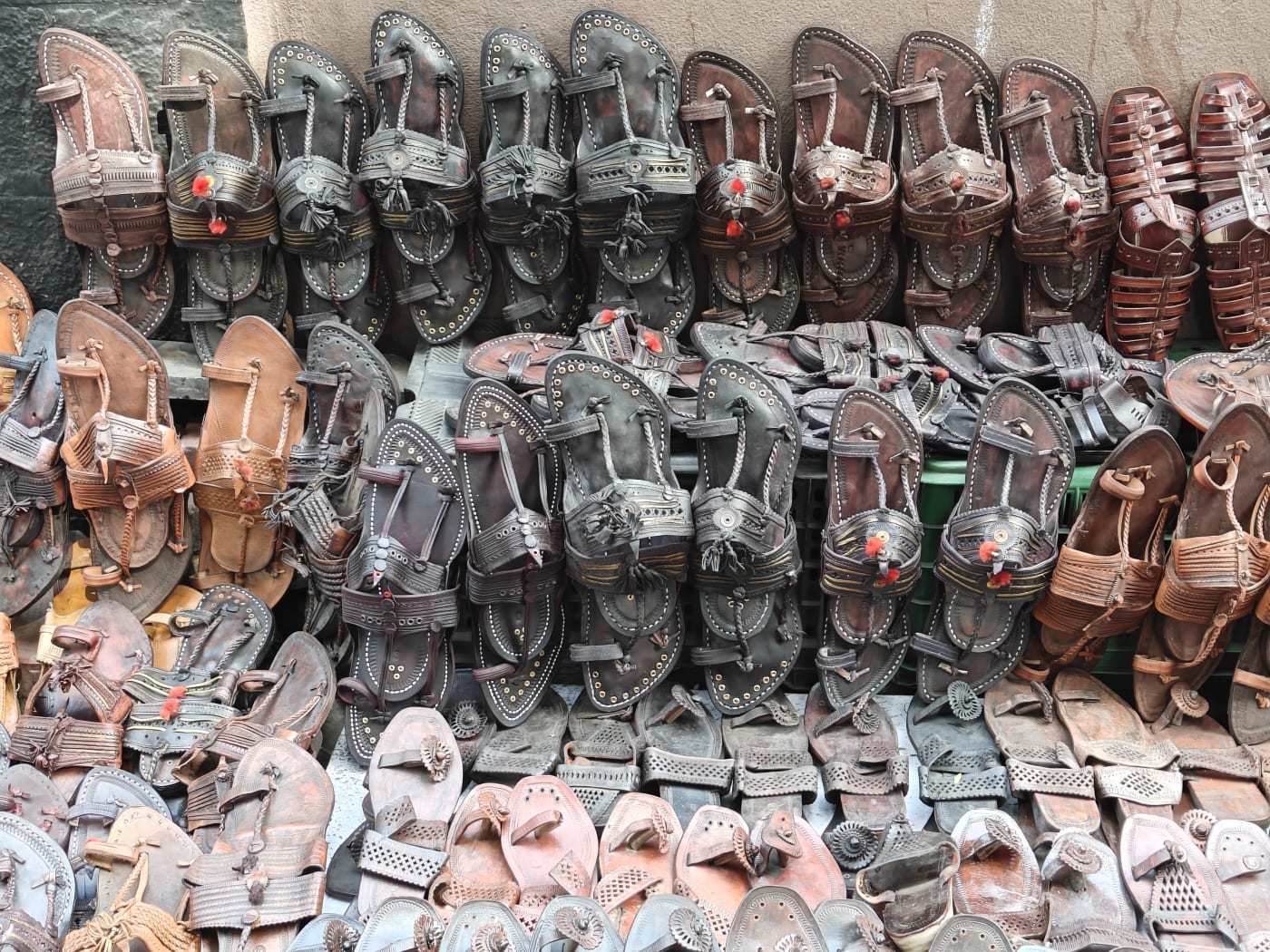 Handcrafted leather Kolhapuri chappals stacked for sale at a shop in Kolhapur, Maharashtra.