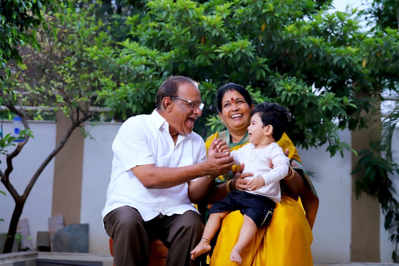 Grandparents with their grandson in a garden in India.