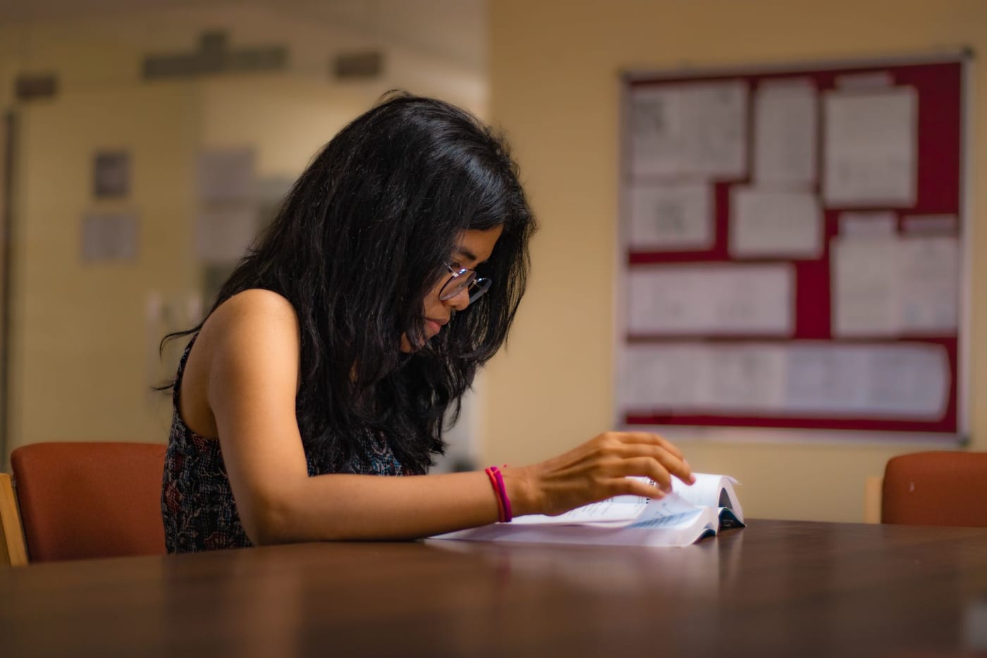A student reading at a university library desk in New Delhi.