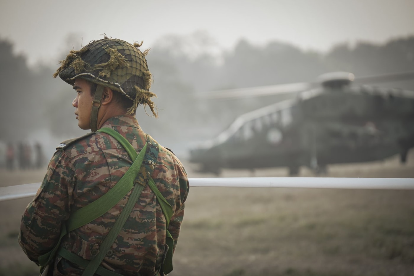 An Indian Army soldier on watch, with a helicopter in the background.