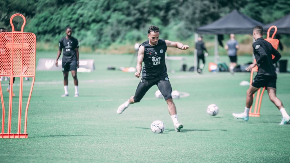 men Athletes practising playing football in the sports field